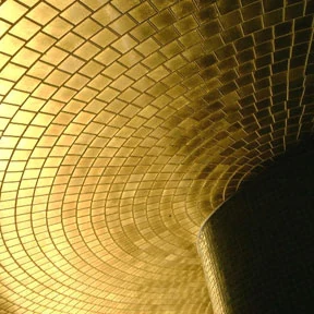 Curved architectural surface finished in gold mosaic tiles